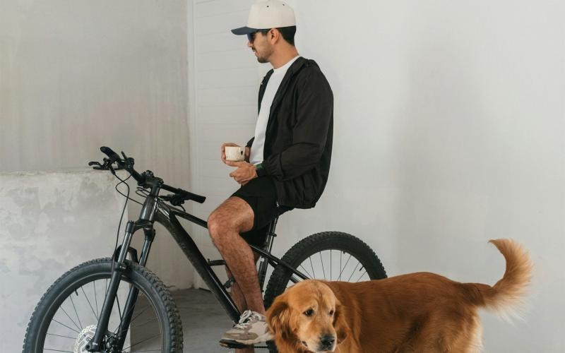 a man sitting on a bike next to a dog